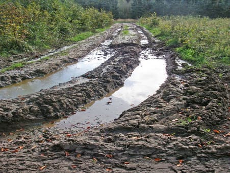 Dybe traktorspor kan være fine til at lægge marksten i. Man skal dog starte med at afgrave det værste løse mudder og jord. Men lad være med at grave en dyb vejkasse. Så skal der alt for mange materialer til, og det bliver i øvrigt også vanskeligt at bakke 